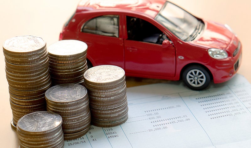 Stacked coins, a red toy car, and a financial ledger with numbers